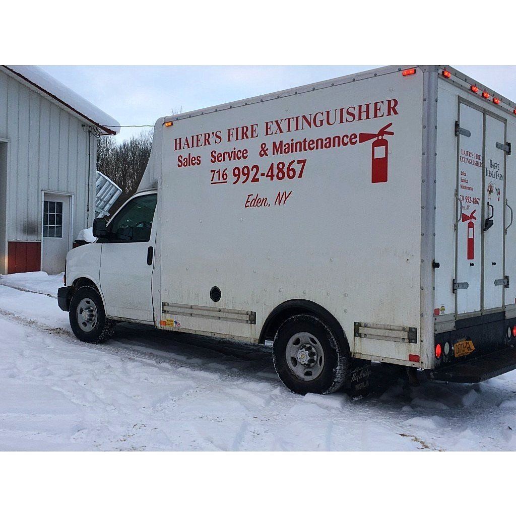 A white fire extinguisher truck is parked in the snow.
