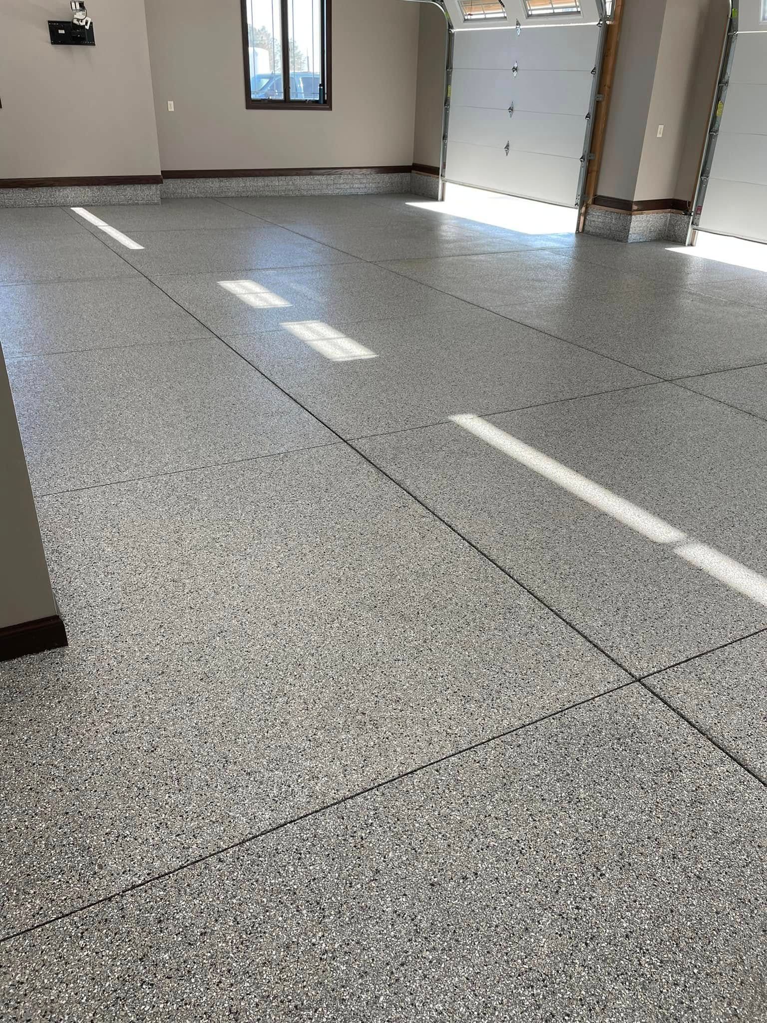 A high-gloss garage floor with a grey, black, and white speckled epoxy flake finish.