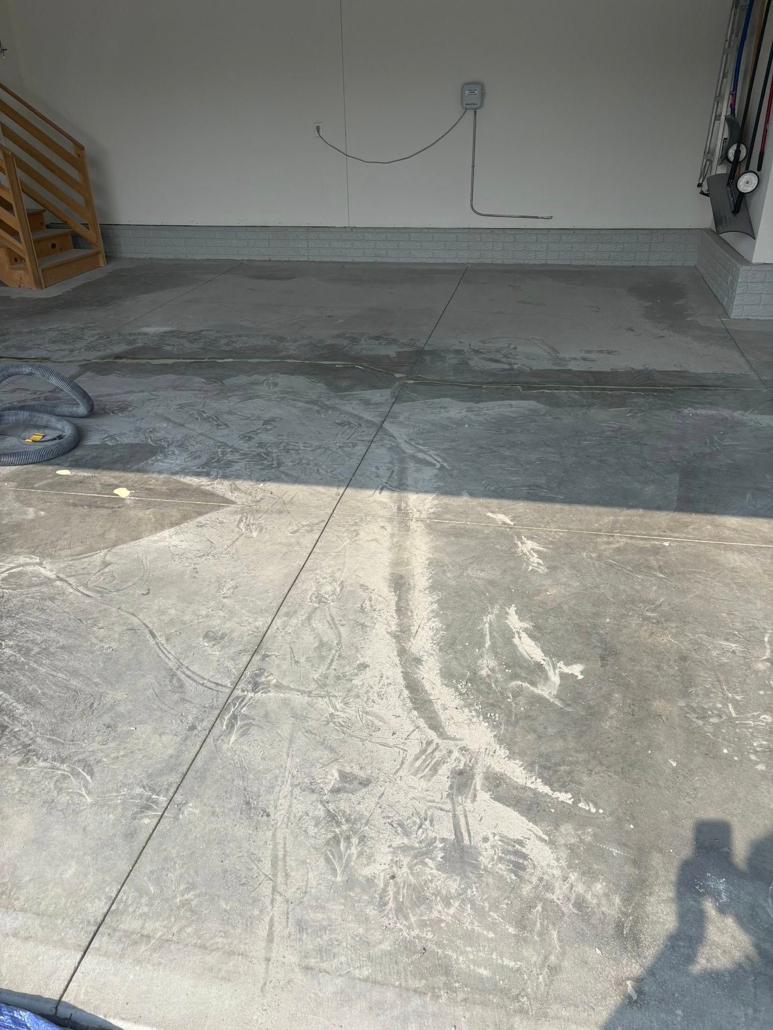 A concrete garage floor with visible cracks, wear, and a shadow cast across the foreground.