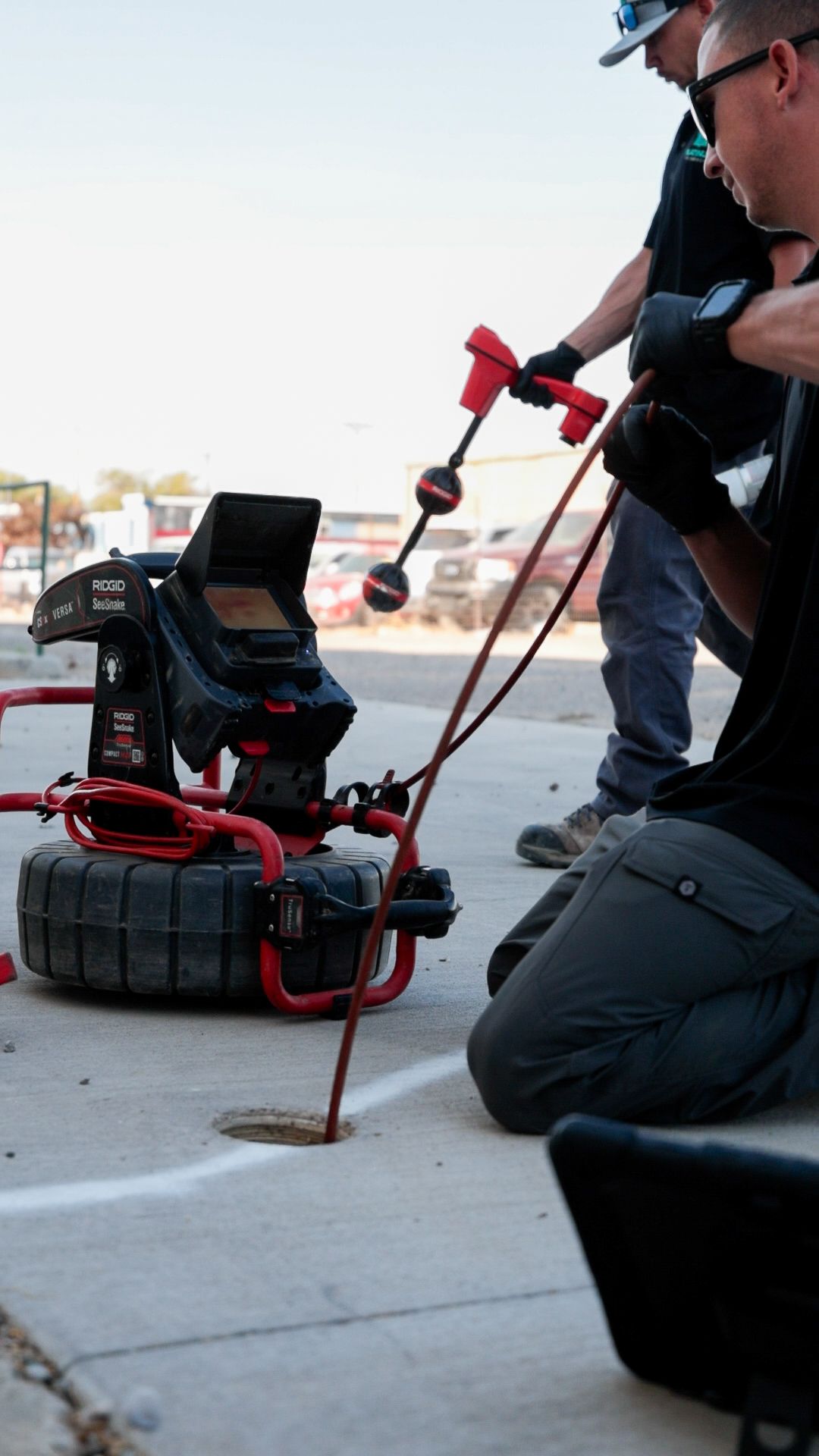 A row of black pipes are being installed in a trench.