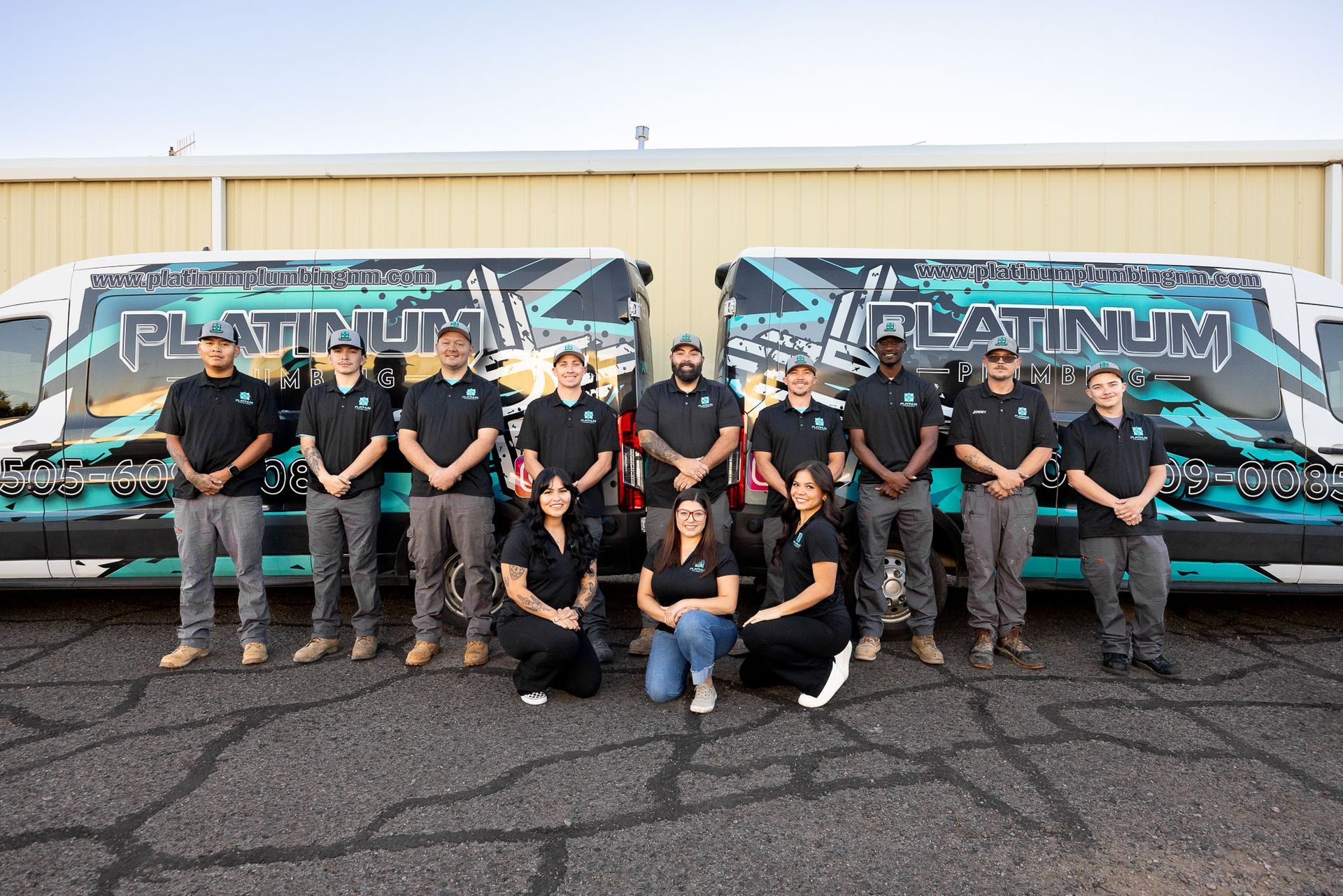 A group of people standing in front of a platinum plumbing van.