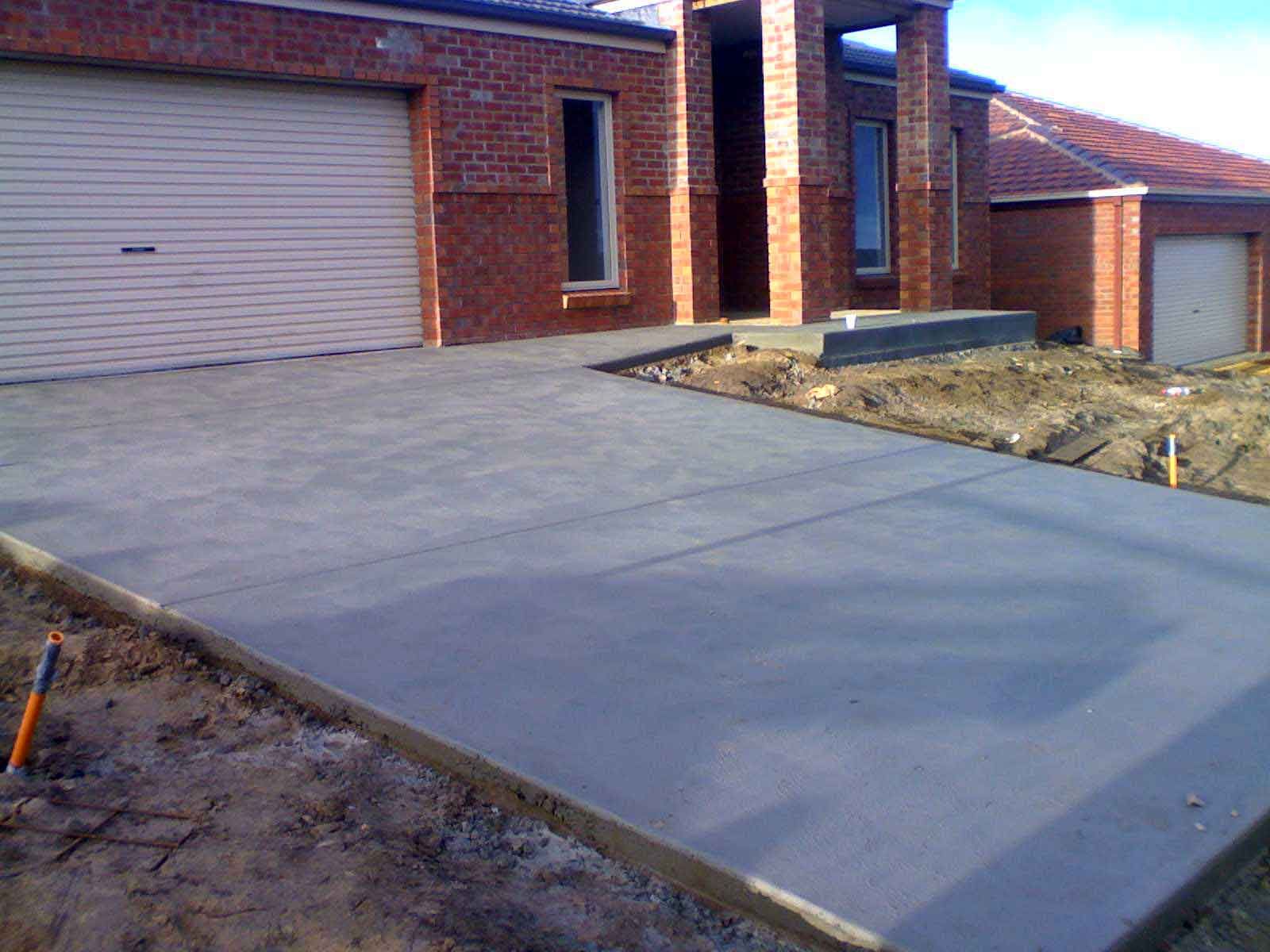 A brick house with a concrete driveway in front of it