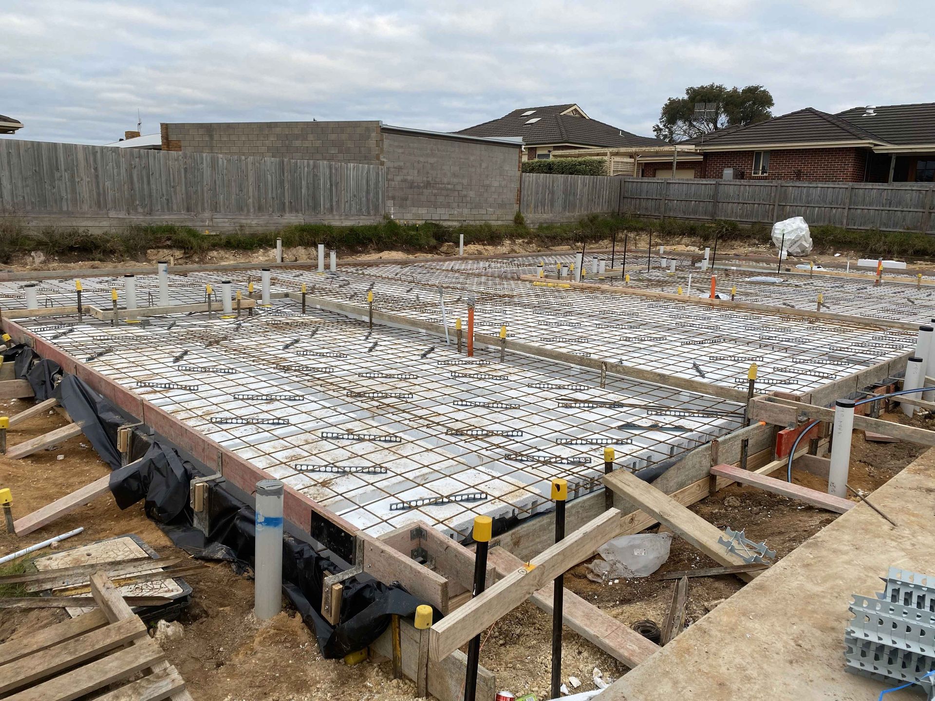 A concrete base for a house is being built on a construction site.