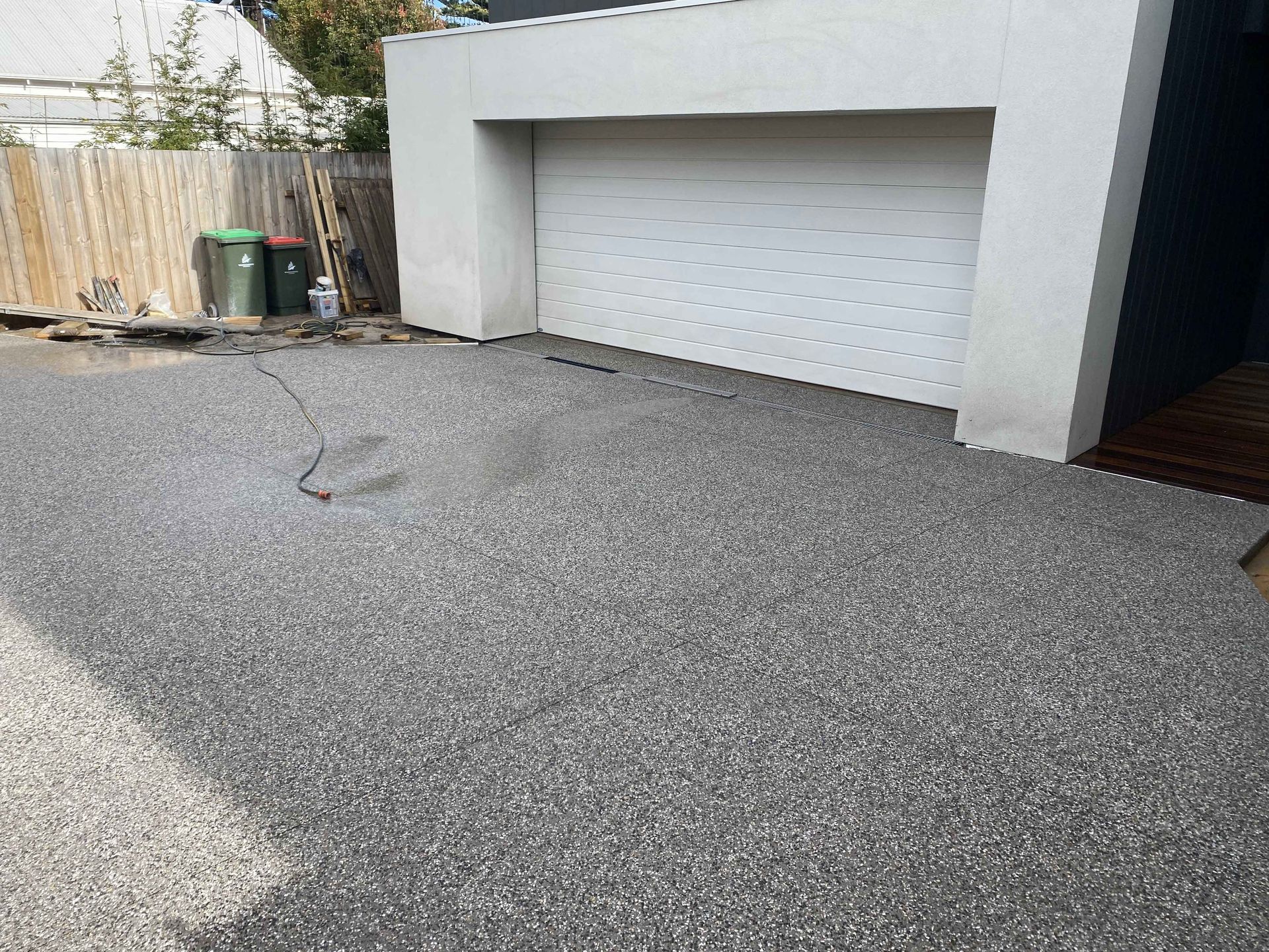 A driveway with a garage door and a fence in the background.