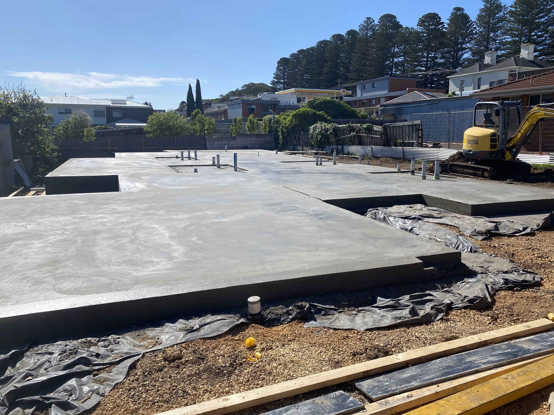 A construction site with a yellow excavator in the background.