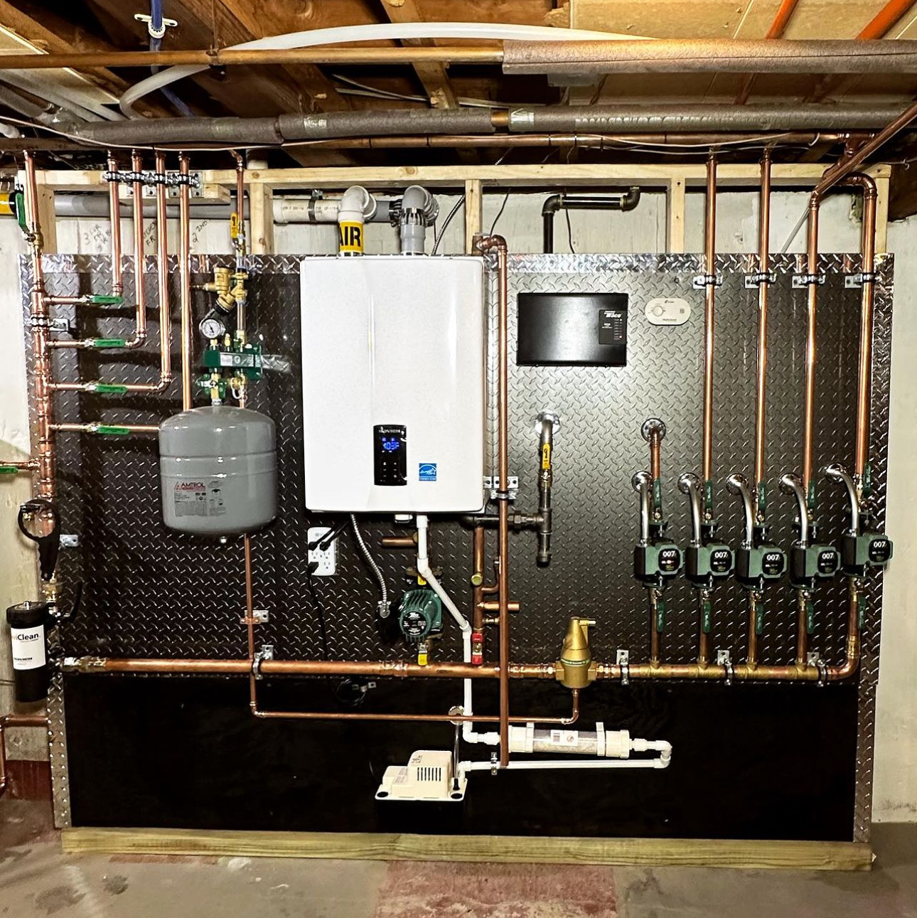 A wall with a lot of pipes and a boiler on it