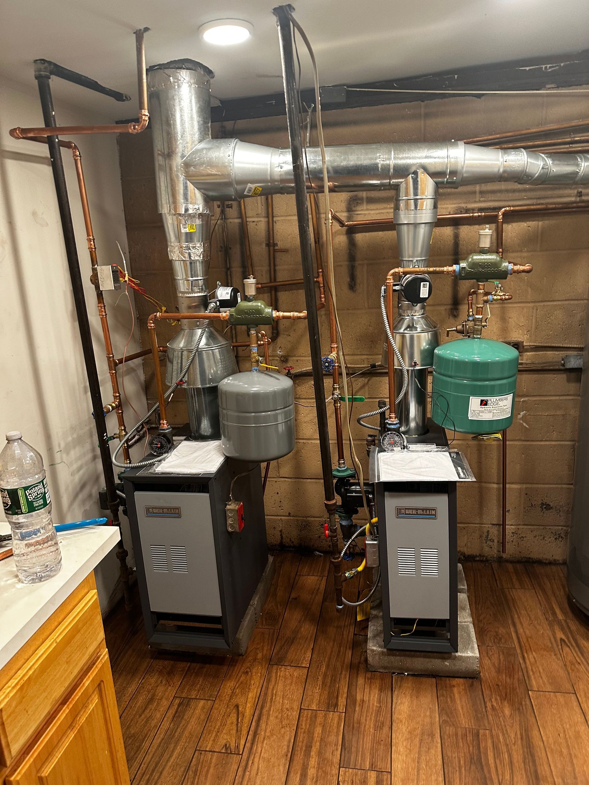 Two boilers are sitting next to each other in a room.