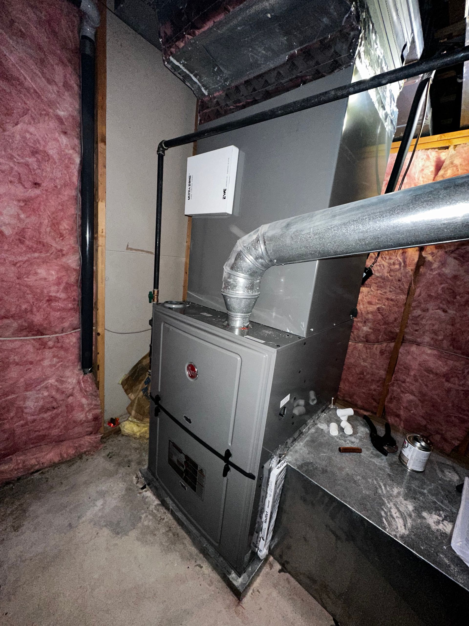An air conditioner is sitting in a room with pink insulation.