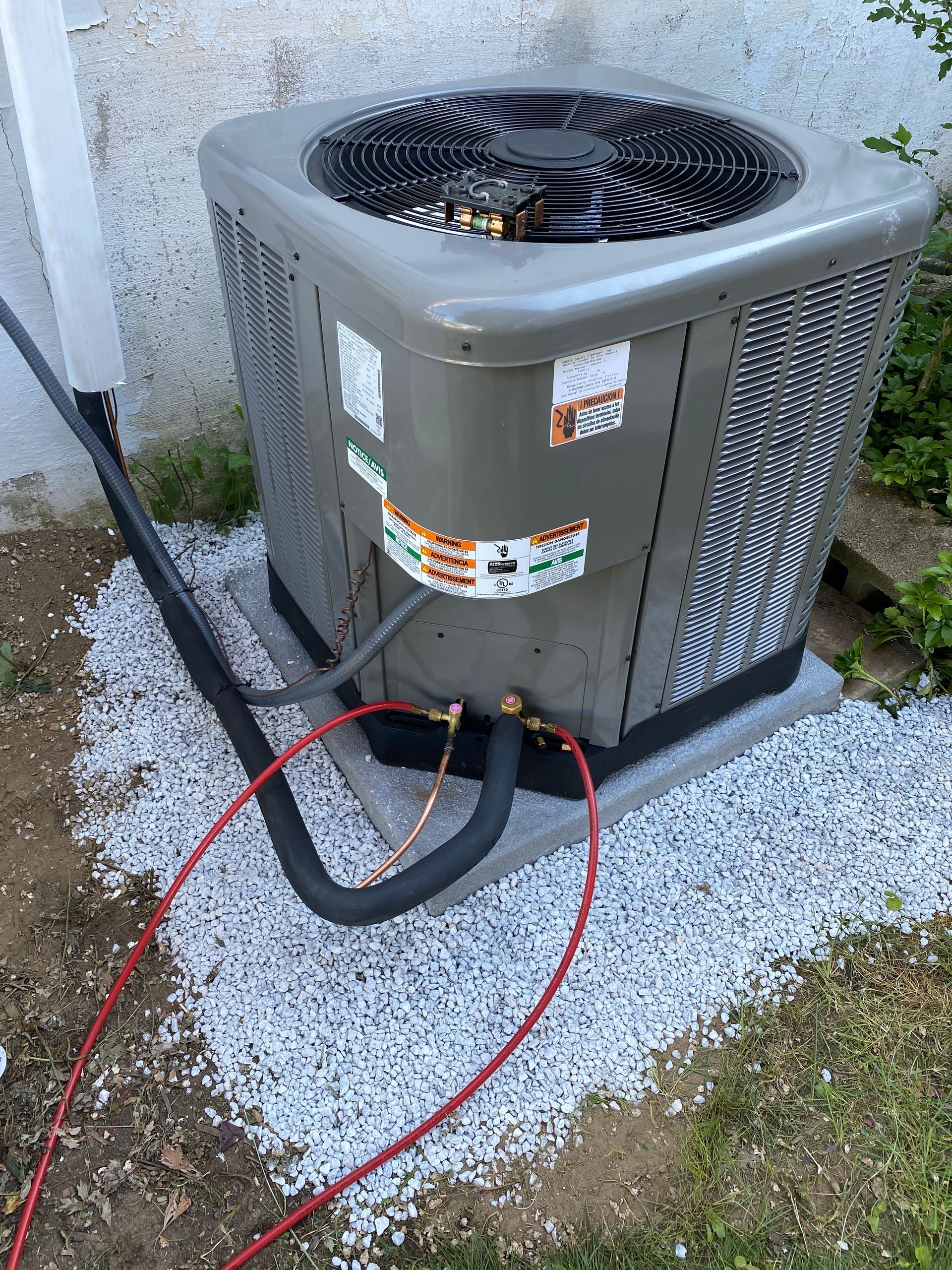 A large air conditioner is sitting on top of a pile of gravel.