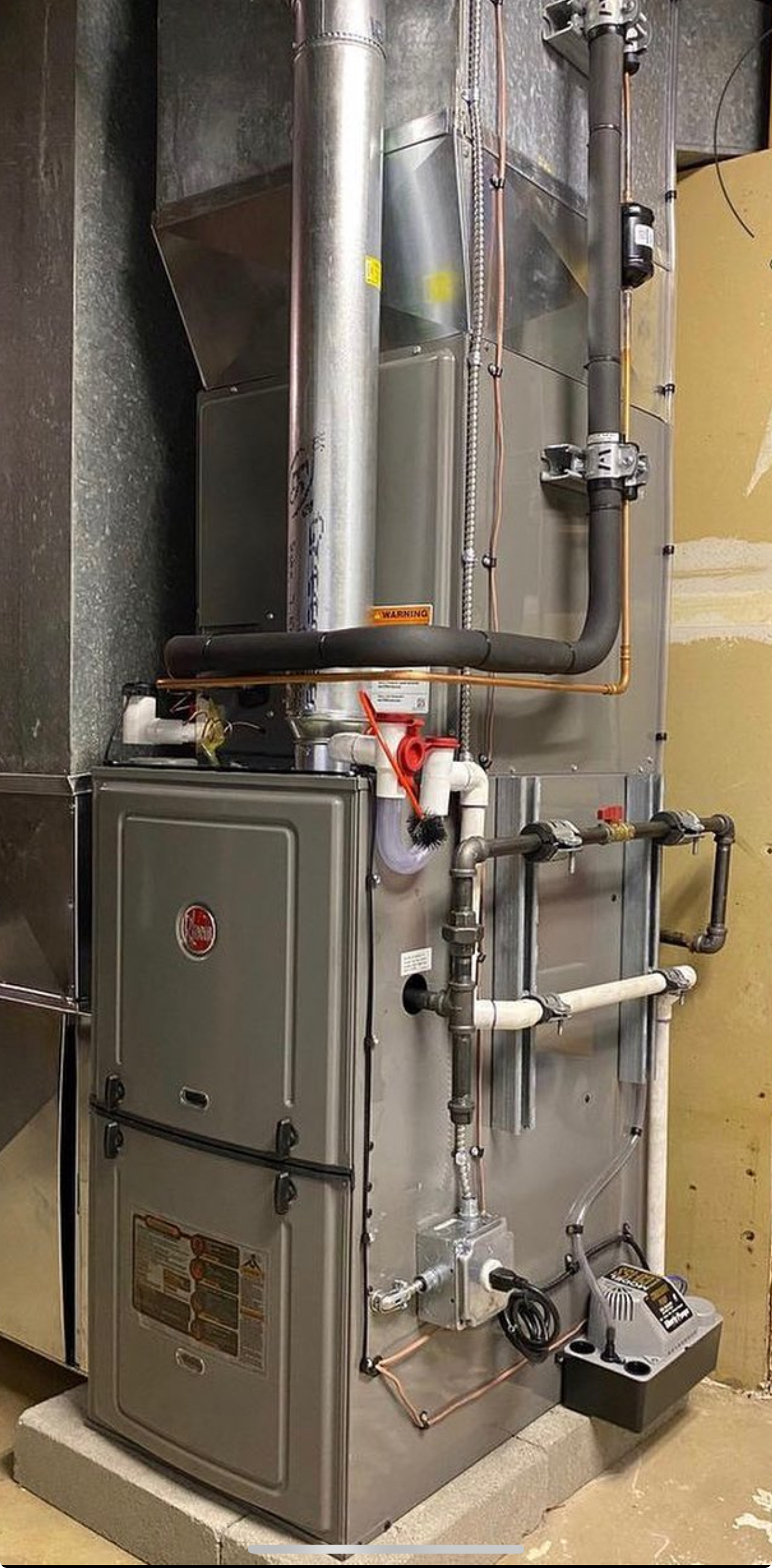 A stainless steel furnace is sitting in a room next to a wall.