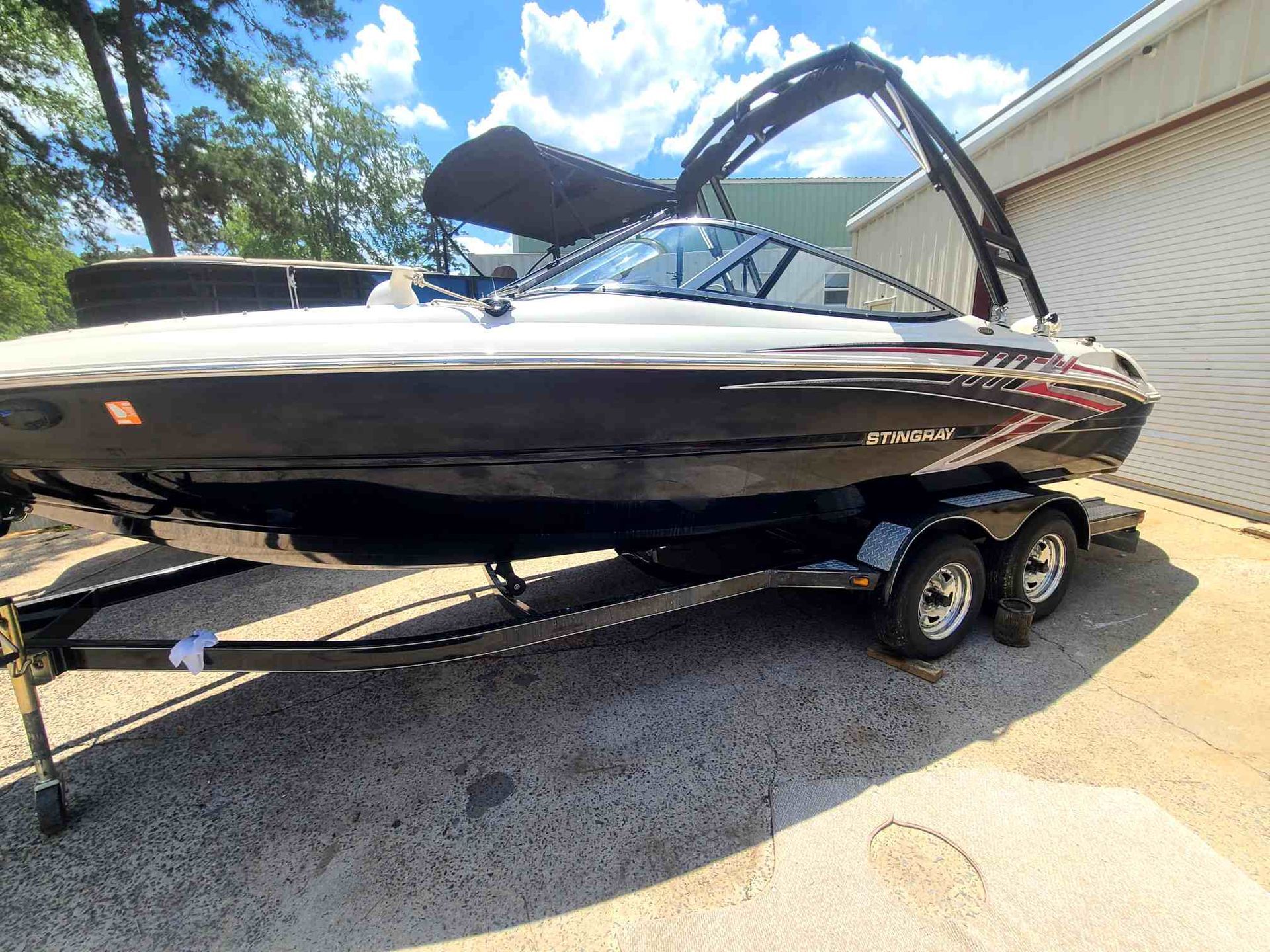 Bow of a white boat on a blue lake, stainless steel railing, distant shoreline under a clear sky.