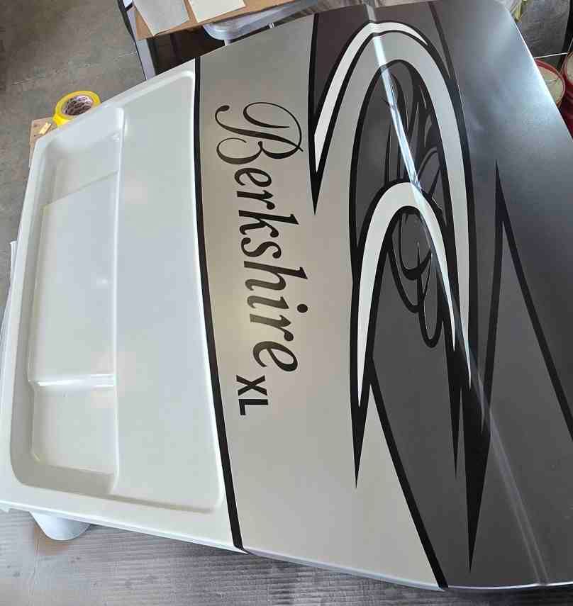 A paintbrush applying blue paint to a dark surface.