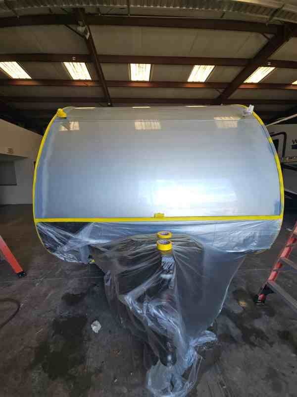 A silver trailer with masking tape and plastic wrap, inside a warehouse.