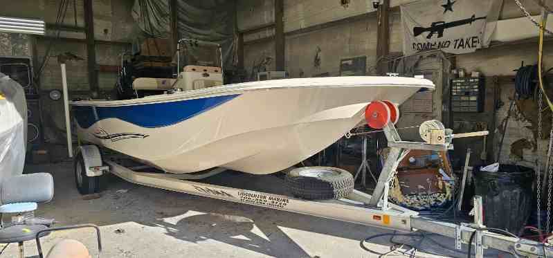 Boat's hull exposed, showing wooden ribs and blue underlay, in a dry dock.