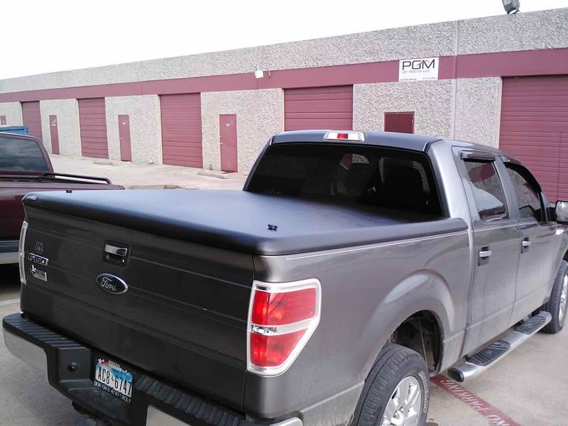 A ford truck with a black tonneau cover is parked in front of a building