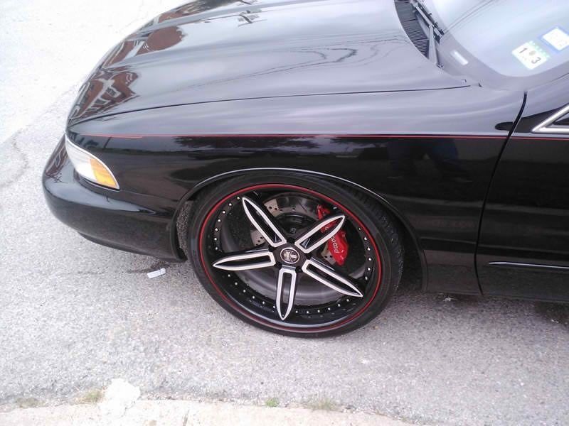 A black car with red rims and brake calipers