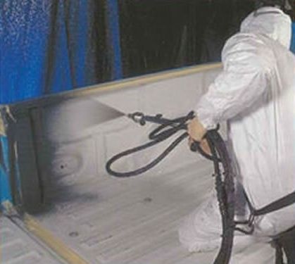 A man in a white suit is spray painting a wall.