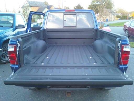 The back of a blue truck with the bed open