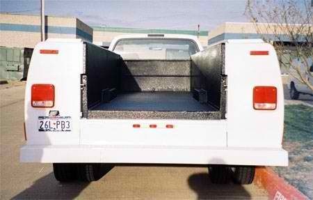 A white truck with the bed open is parked in a parking lot.