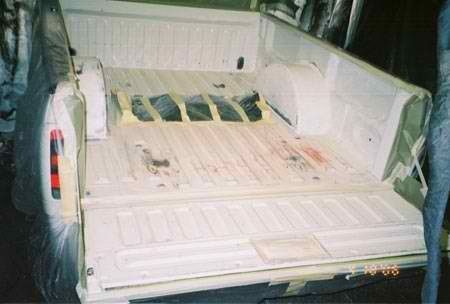 The back of a truck is being painted white.