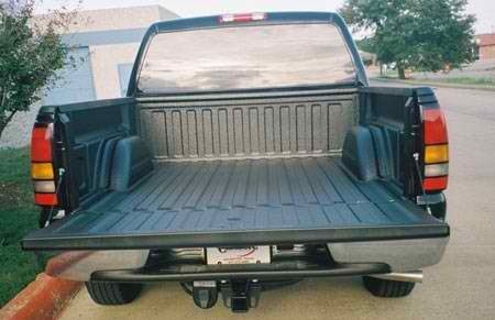 A black truck with the bed open is parked on the side of the road.
