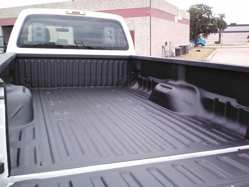A white truck with a black bed is parked in front of a building