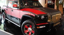 A red and black truck is parked in a showroom.
