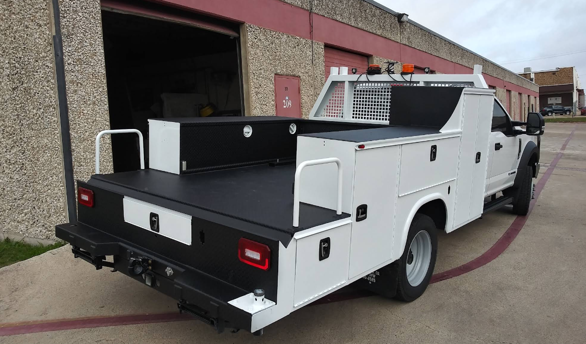 A white utility truck is parked in front of a building.
