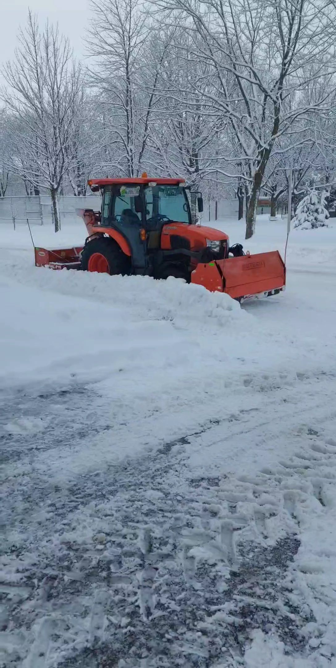 Un camion déneige une route enneigée.