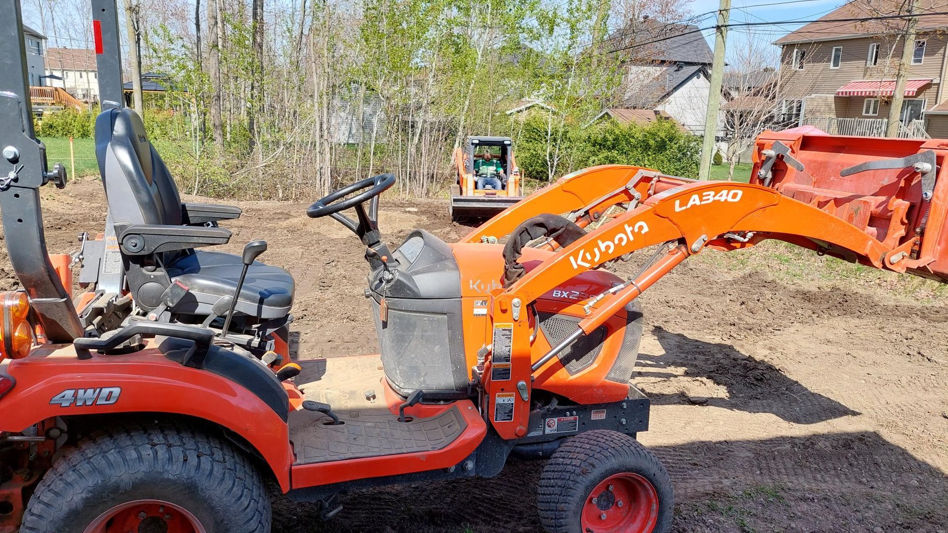 Un tracteur avec un chargeur attaché est garé dans un champ de terre.