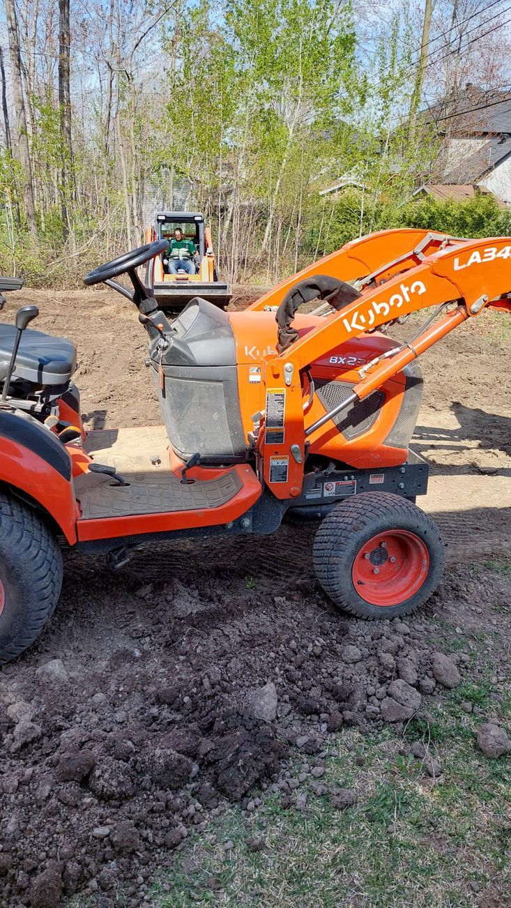 Un tracteur avec un chargeur attaché est assis dans la terre.