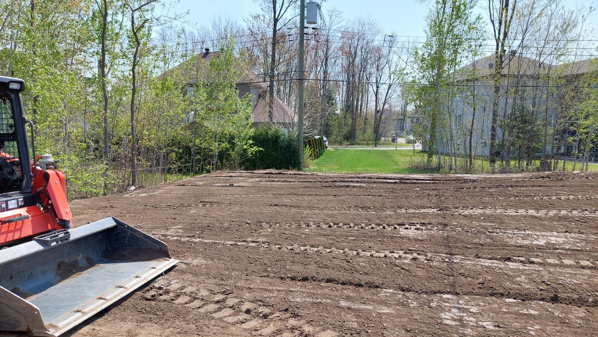 Un bulldozer déplace de la terre dans un champ devant une maison.