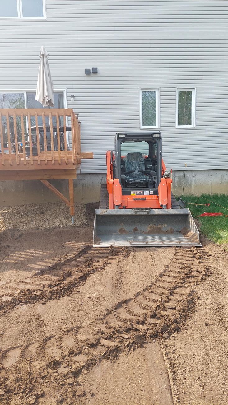 Un bulldozer est assis sur un champ de terre devant une maison.