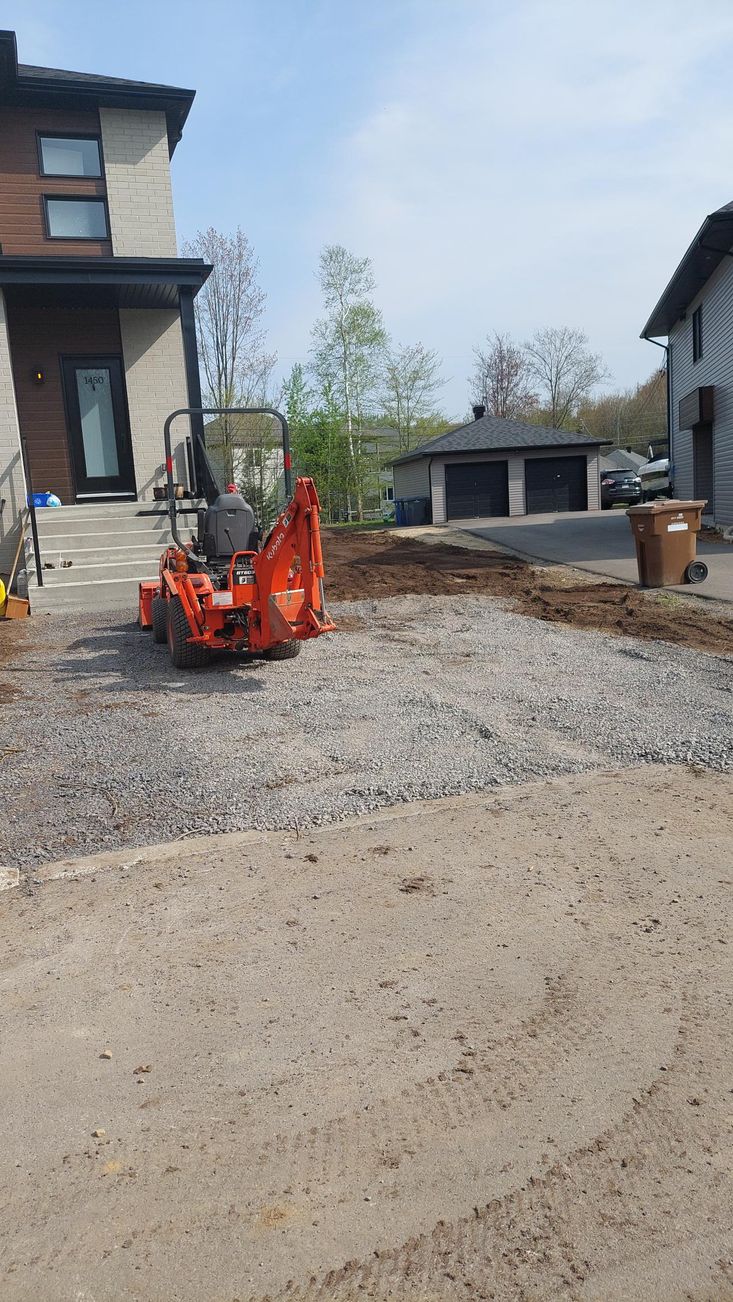Un petit tracteur orange est garé devant une maison.