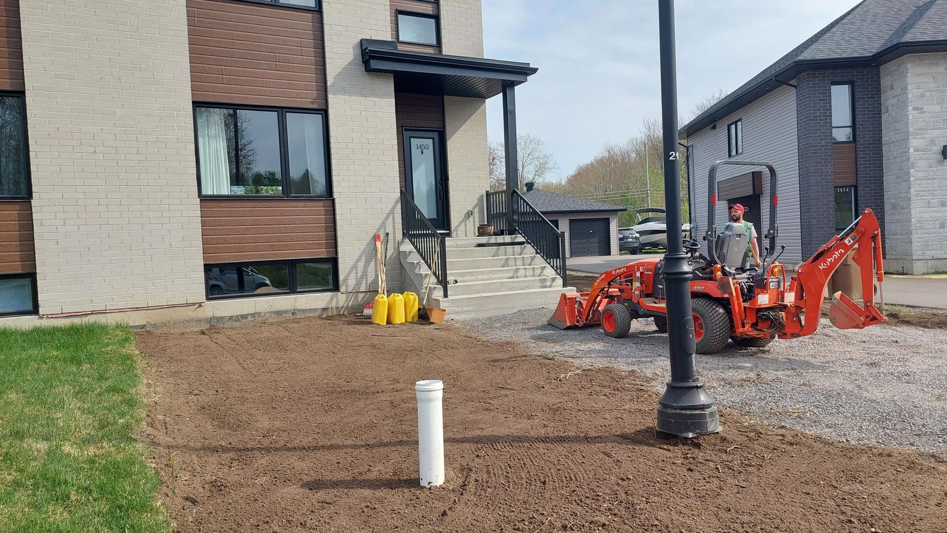 Un homme conduit un tracteur rouge devant une maison.