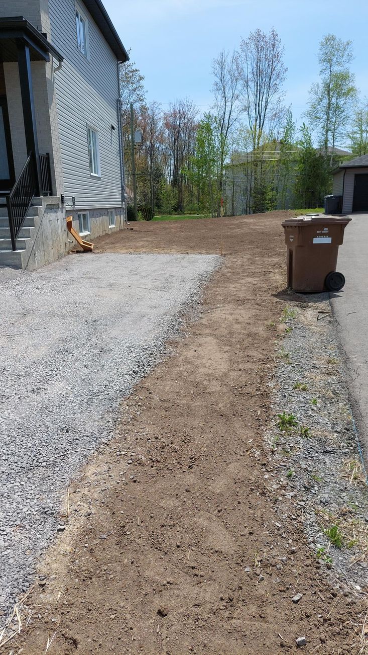 Il y a une poubelle sur le côté de la route à côté d'une maison.