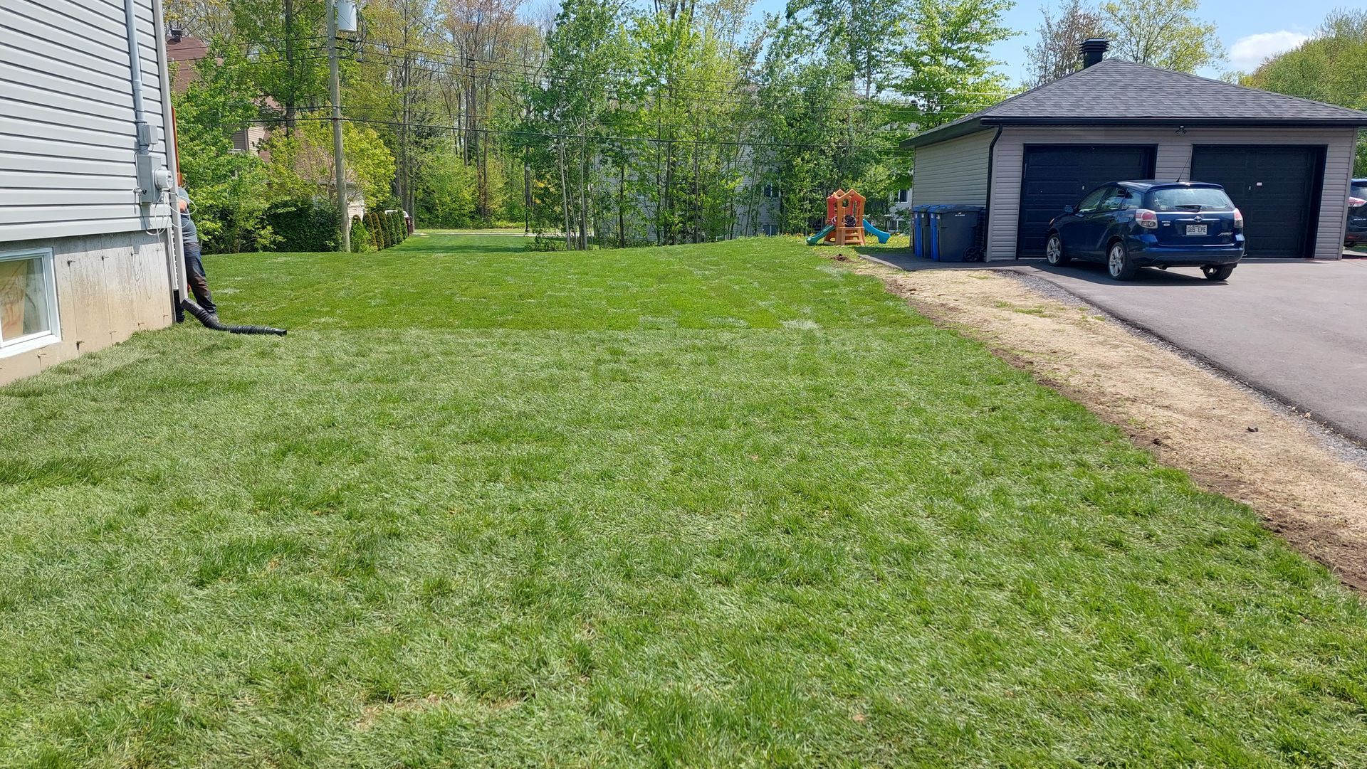 Une voiture est garée dans l'allée d'une maison à côté d'une pelouse verte luxuriante.