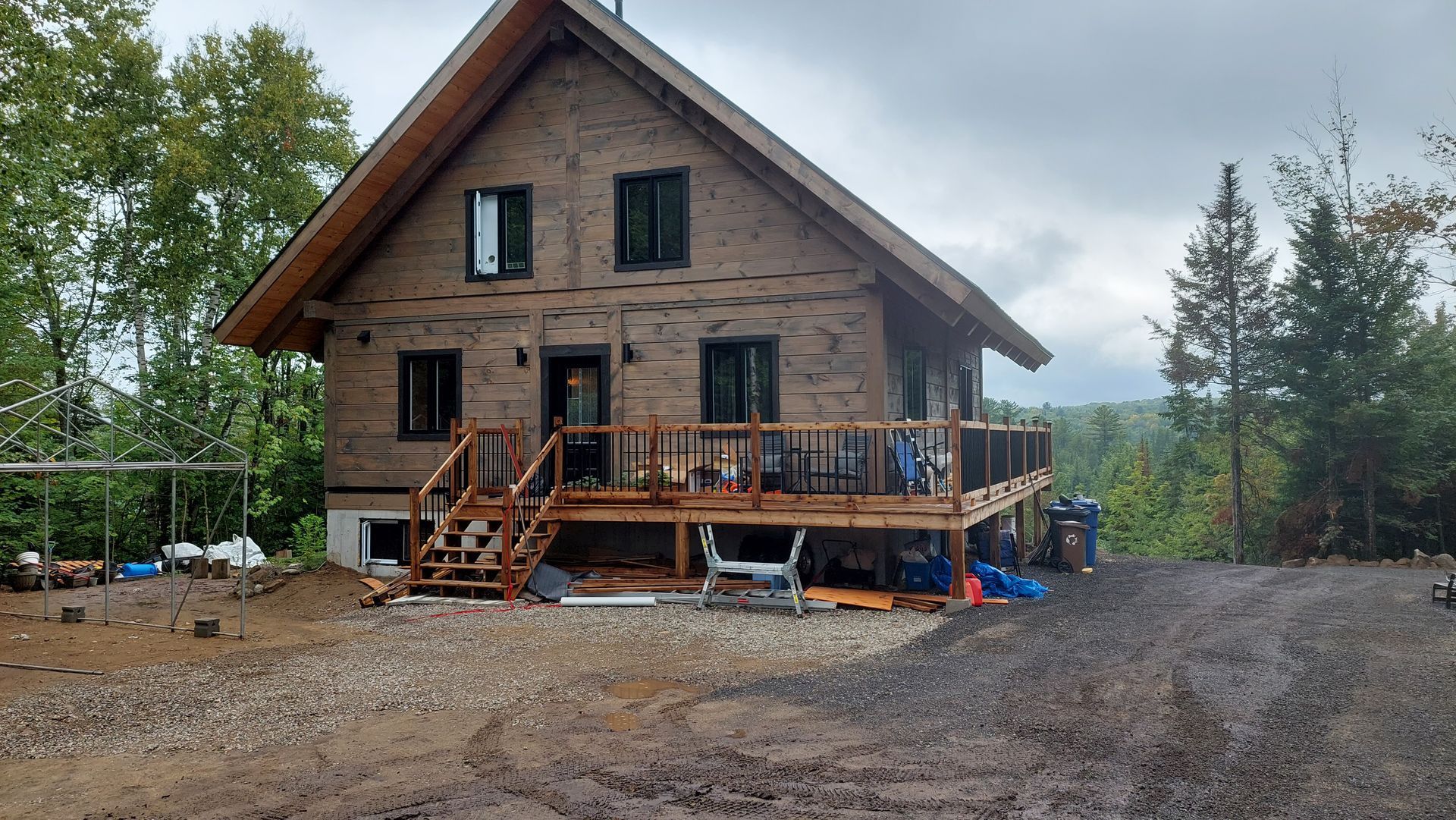 Une grande maison en bois avec une grande terrasse au milieu d'une forêt.