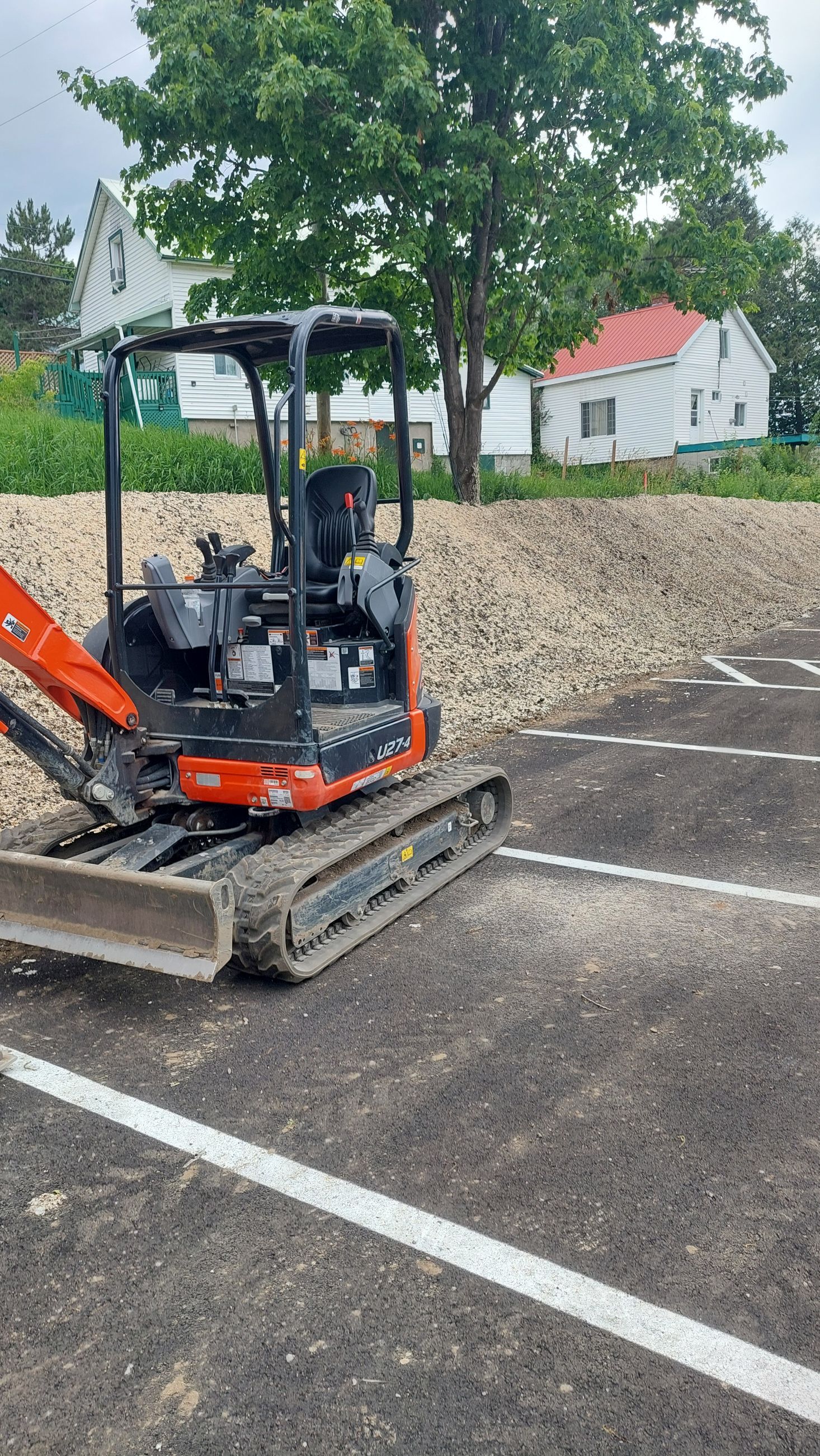 Une petite excavatrice est garée sur un parking.