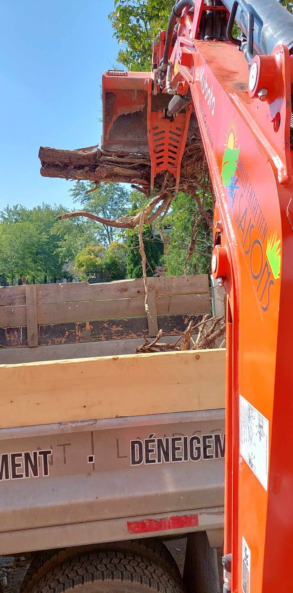 Une excavatrice rouge charge de la terre dans un camion.