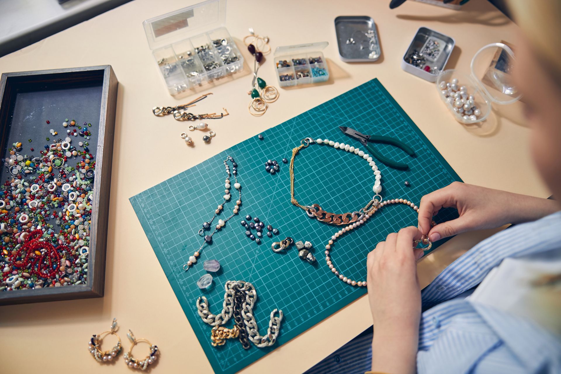 A person is sitting at a table making jewelry.