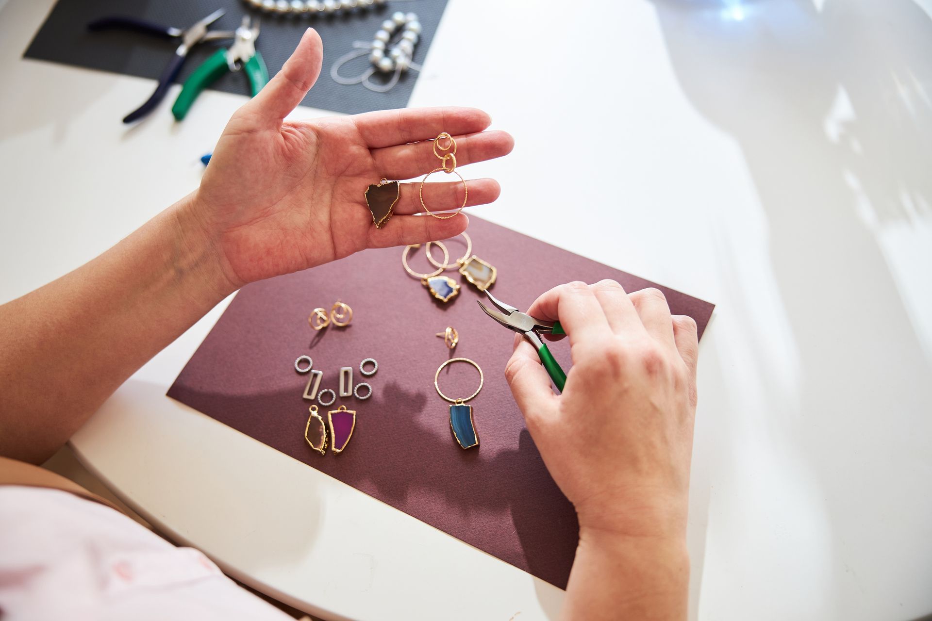 A woman is sitting at a table making jewelry.