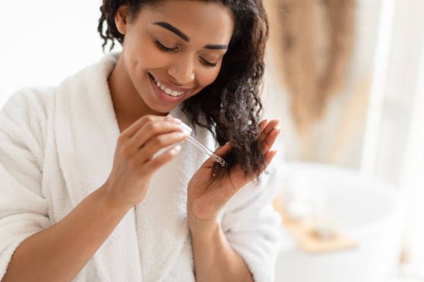 A woman is applying cream to her face in front of a mirror.