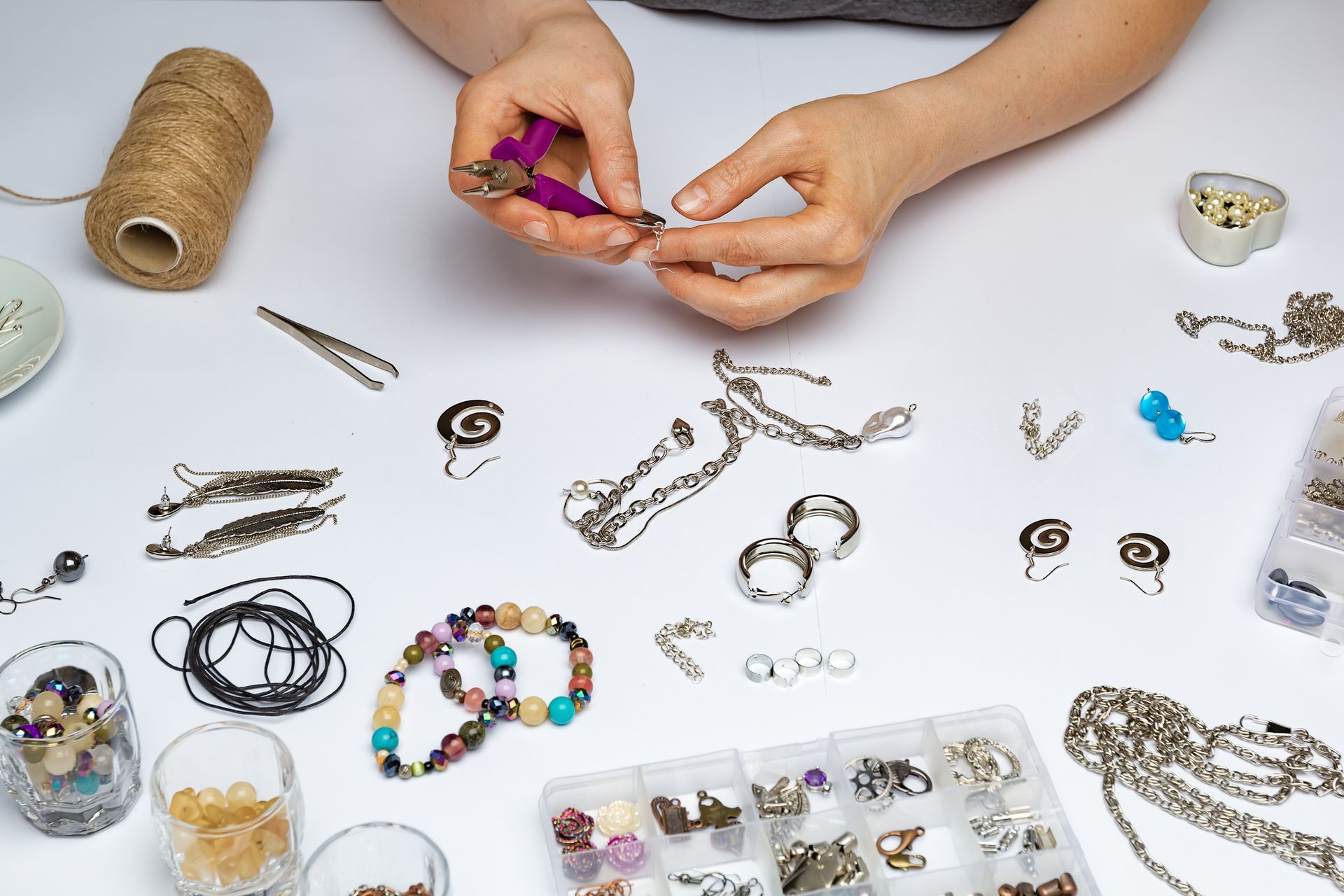 A woman is making a bracelet with a pair of pliers.