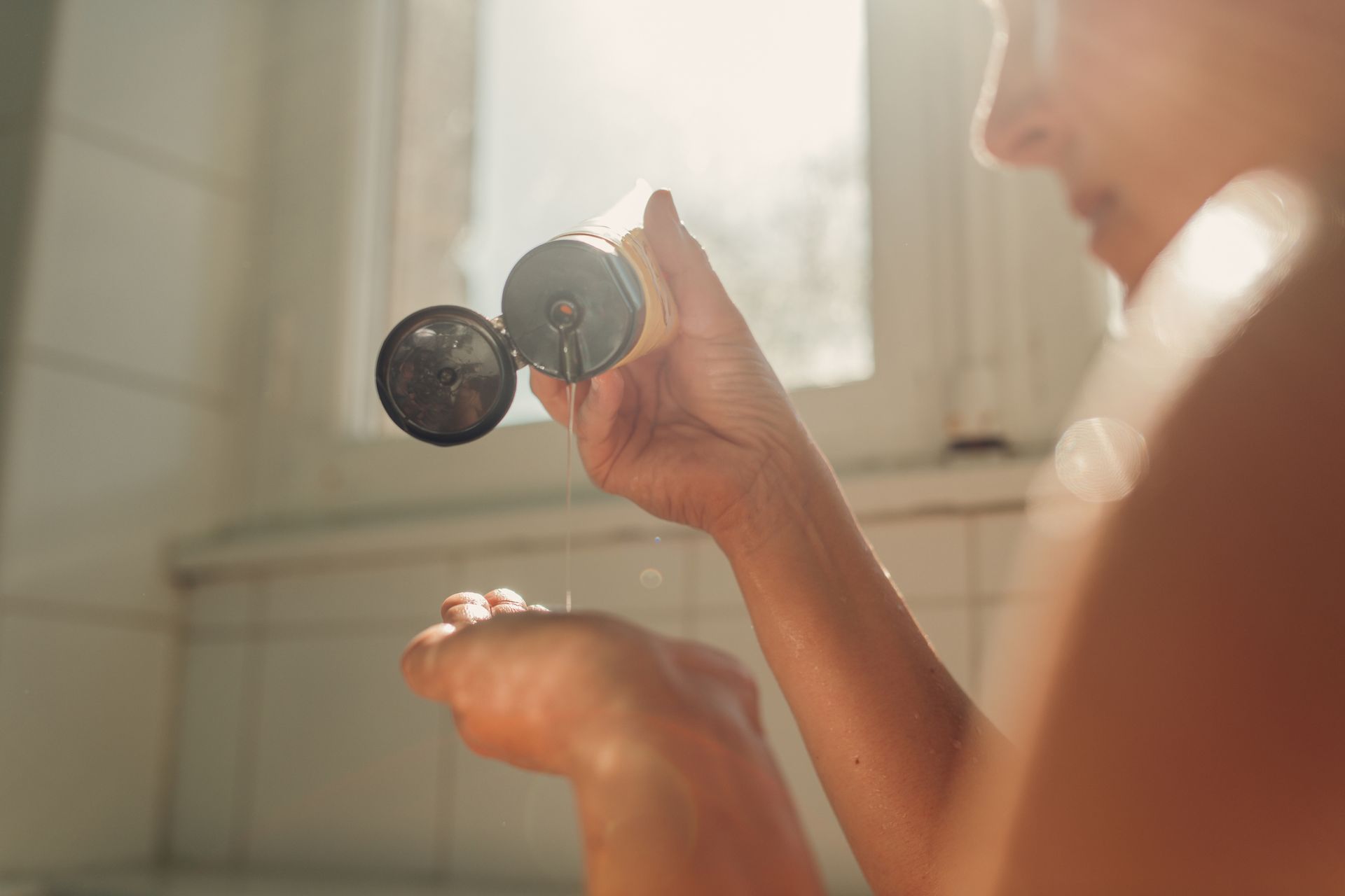 A woman is holding a bottle of lotion in her hand.