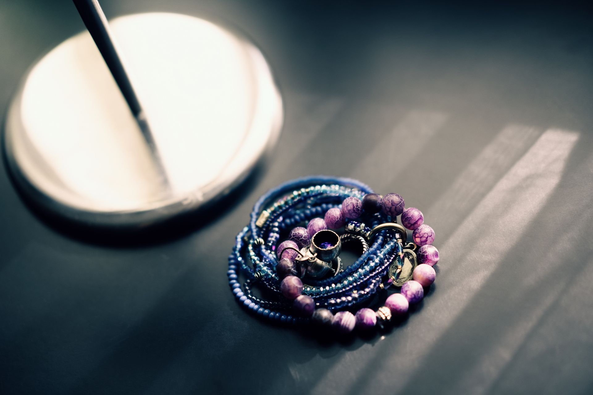 A stack of bracelets and rings on a table next to a lamp