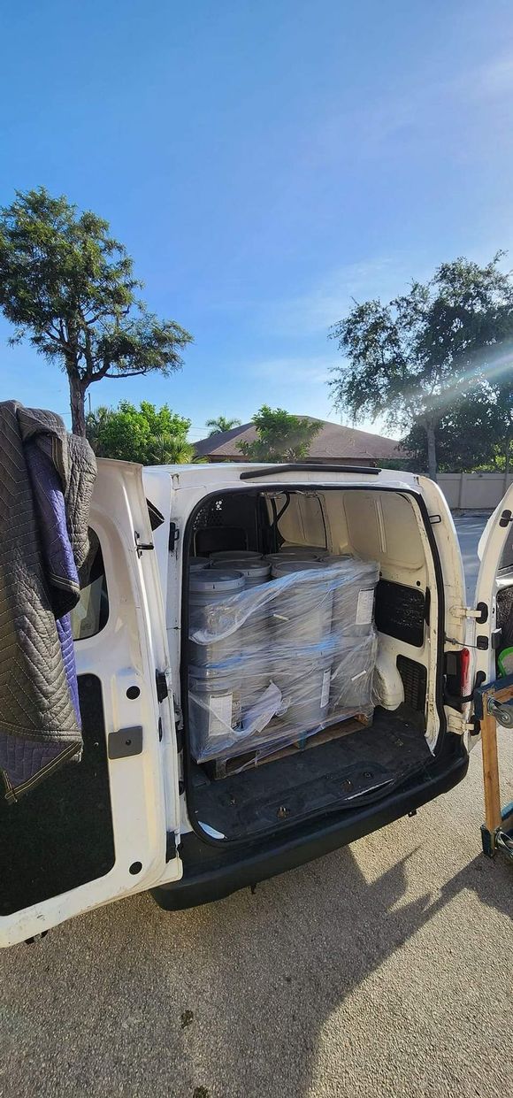 The back of a white van is filled with buckets of toilet paper.