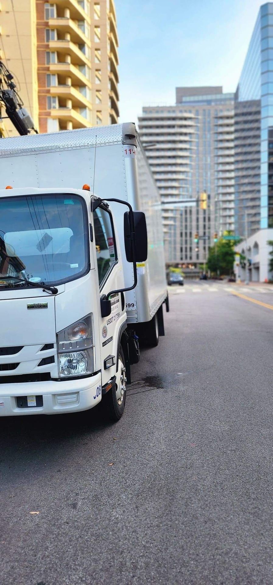 A white truck is parked on the side of a city street.