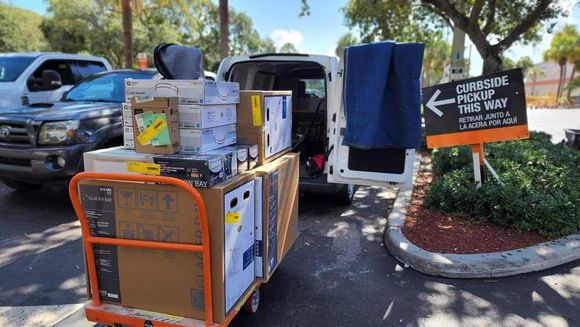 A white van is loaded with boxes and a cart.