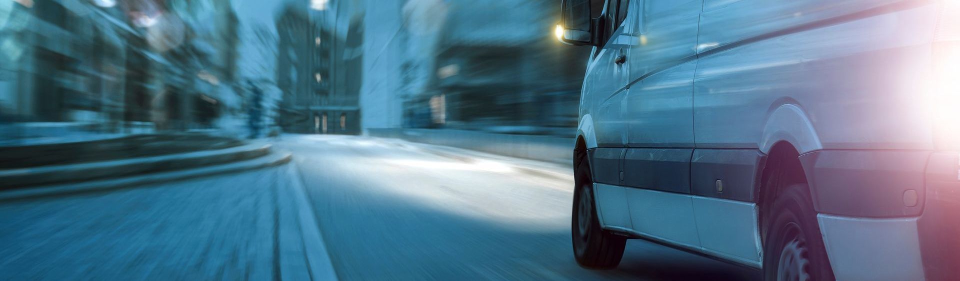 A van is driving down a city street at night.